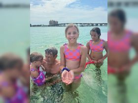 A joyful moment as children interact with marine life while swimming in shallow waters, showcasing a delightful family experience in a tropical setting.