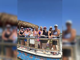 A lively group of women poses together on the deck of a boat, celebrating friendship and fun in the sun — perfect for bachelorette parties or girls' trips.