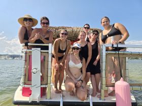 A lively group of friends enjoys a fun day on the water, posing together on a boat, perfect for celebrations and summer outings.