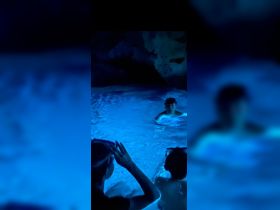 A group of young swimmers enjoys a magical underwater experience in a glowing cave, perfect for snorkeling adventures.
