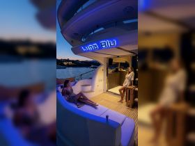 Two women relax in the stylish lounge area of the 'Luna Blu' yacht, showcasing the elegant interior design perfect for evening gatherings on the water.