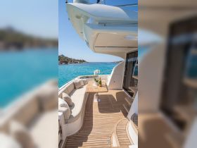 A beautifully designed lounge area on a yacht, featuring comfortable seating and a table set for relaxation, perfect for enjoying the stunning turquoise waters.