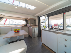 A modern and spacious interior of a boat featuring a cozy dining area with a fruit bowl, perfect for relaxing and enjoying meals while at sea.