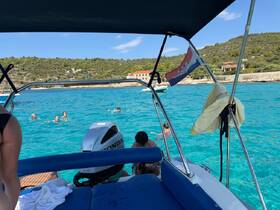 A lively group enjoys swimming in the crystal-clear turquoise waters, with a boat providing the perfect backdrop for a fun day on the water.