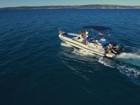 A sleek speedboat navigates through clear blue waters, showcasing its design and performance under a sunny sky.