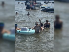 A lively group enjoys a fun day in the water, celebrating with drinks and floating mats near their pontoon boats — perfect for summer parties and relaxation.