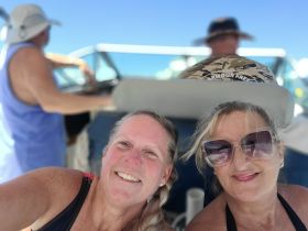 Two friends enjoy a sunny day on the boat, capturing a joyful moment together. Perfect for showcasing fun outings and group adventures on the water.
