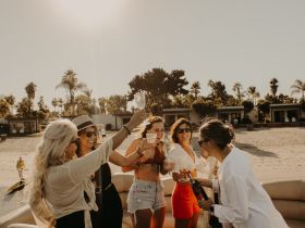 A lively group of friends celebrates with cocktails on a boat, capturing the essence of fun and friendship in a beautiful beach setting.