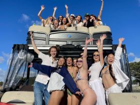 A lively group of friends celebrates together on a boat, showcasing joy and camaraderie under a sunny sky — perfect for unforgettable summer outings.