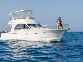 A couple enjoys a sunny day aboard a yacht, cruising through clear waters — perfect for romantic getaways or summer adventures.