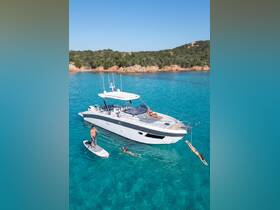 A lively scene featuring friends enjoying a day on the water with paddleboarding and swimming near a sleek boat, set against a stunning coastal backdrop.