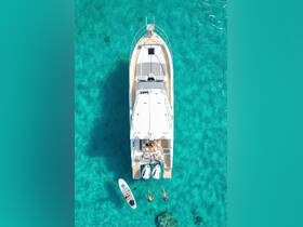An aerial view of a luxurious yacht anchored in stunning turquoise waters, with guests enjoying paddleboarding and swimming — a perfect scene for summer adventures.