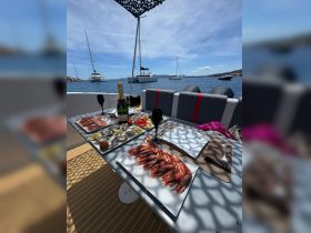 A beautifully arranged seafood platter featuring shrimp and oysters, complemented by champagne and cocktails, perfect for a luxurious dining experience on the water.