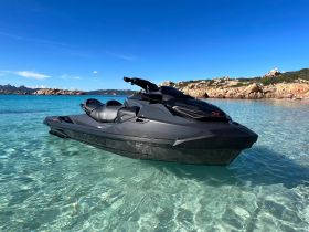 A sleek jet ski rests in crystal-clear waters, showcasing its design against a stunning coastal backdrop — perfect for water sports enthusiasts.