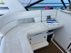 Interior view of a comfortable seating area on a boat, featuring plush white upholstery and neatly arranged towels, perfect for relaxing on the water.