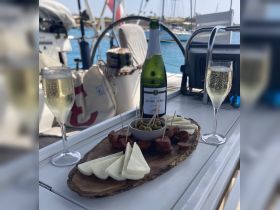 A beautifully arranged charcuterie board featuring cheese, chorizo, and olives, paired with sparkling Cava, perfect for enjoying onboard a yacht.