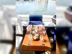 A beautifully arranged table on a boat featuring wine, appetizers, and a cozy atmosphere, perfect for enjoying a relaxing day on the water.