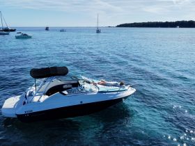 A person relaxes on the deck of a sleek boat, enjoying the sun and serene waters — an ideal scene for leisure and relaxation on the water.