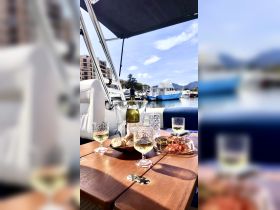 A beautifully arranged table on a boat featuring wine, snacks, and a picturesque marina view — perfect for a relaxing day on the water.
