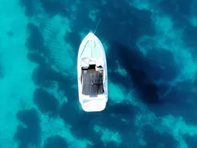 A stunning aerial view of a boat gliding over crystal-clear turquoise waters, showcasing the vibrant underwater scenery — perfect for exploring coastal destinations.
