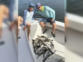 Two anglers proudly display their impressive catch of fish aboard a boat, showcasing a successful day of fishing on the water.