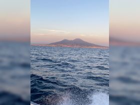 A stunning view of Mount Vesuvius from the water, showcasing the natural beauty and iconic landscape of the region during sunset.