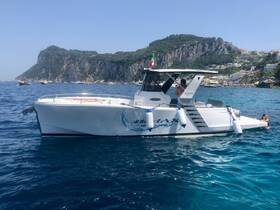 A group enjoys a sunny day on the water, with one person swimming next to a sleek boat against a stunning coastal backdrop.