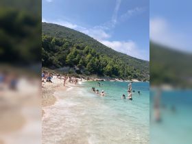 A vibrant beach scene with groups of people enjoying the clear waters and sunshine — perfect for summer fun and relaxation.