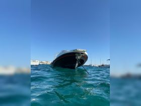 A striking view of a boat anchored in clear turquoise waters, showcasing its sleek design against a bright blue sky — perfect for a day out on the water.