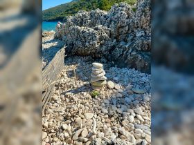A serene scene featuring stacked stones on a rocky beach, surrounded by pebbles and greenery, perfect for nature lovers and beachcombers.