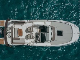 An aerial view of the spacious interior of a boat, showcasing comfortable seating and a well-equipped helm, perfect for a day out on the water.