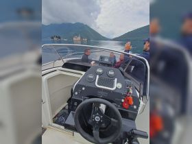 A group of friends enjoys a scenic boat ride with stunning mountain views in the background, perfect for exploring beautiful waterways.