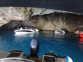 A captivating view of several boats inside a stunning cave, showcasing a group enjoying the scenic beauty of the water and rock formations.