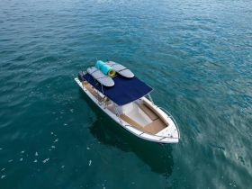 Aerial view of a sleek speedboat cruising through clear turquoise waters, perfect for water sports and leisurely outings.