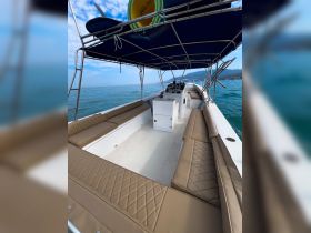 Interior view of a spacious boat cabin featuring comfortable seating and a helm, perfect for relaxing while enjoying a day on the water.