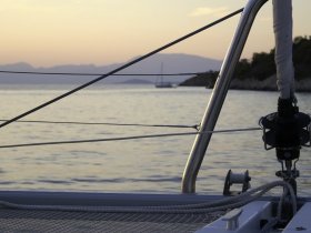 A serene view of a catamaran's deck with a backdrop of calm waters and distant mountains, perfect for showcasing the beauty of sailing adventures.