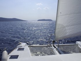 A stunning view from the deck of a catamaran sailing through sparkling waters, showcasing the serene beauty of the surrounding landscape.