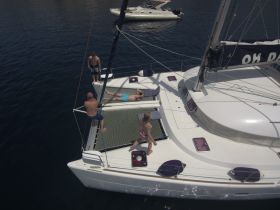 A lively group enjoys a day on a catamaran, with activities like sunbathing and swimming, showcasing the perfect blend of relaxation and fun on the water.