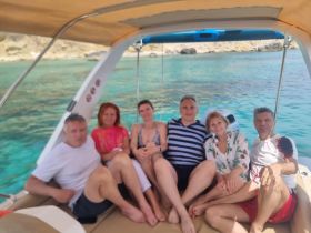 A cheerful group of friends relaxes aboard a boat, enjoying the stunning turquoise waters — perfect for memorable outings and celebrations.