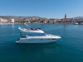 A sleek yacht glides through clear waters, showcasing its elegant design against a picturesque coastal backdrop — perfect for luxury charters and scenic tours.