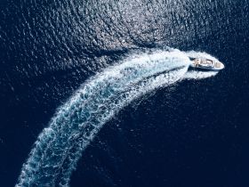 An aerial view of a sleek speedboat carving through deep blue waters, showcasing the thrill of boating adventures.