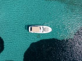 A stunning aerial view of a yacht gliding over crystal-clear turquoise waters, perfect for showcasing luxury boating experiences.