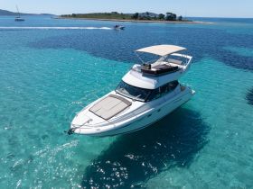 A stunning aerial view of a sleek yacht cruising through crystal-clear turquoise waters, perfect for luxury getaways and island explorations.