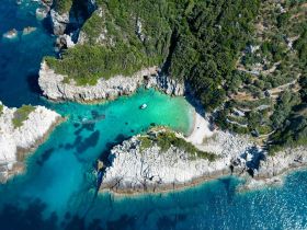 A stunning aerial view of a secluded beach surrounded by rocky cliffs and crystal-clear waters, perfect for exploring and relaxing in nature.