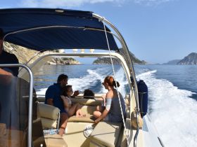 A family enjoys a scenic boat ride, capturing the joy of togetherness on the water amidst beautiful coastal views.