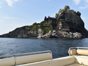 A picturesque view of a rocky island with lush greenery, captured from a boat — an ideal scene for exploring coastal destinations.