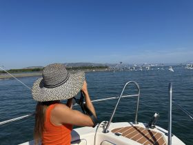 A woman captures the beauty of nature from a boat, surrounded by flying birds and stunning scenery — a perfect moment for photography enthusiasts.