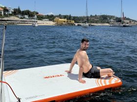 A man enjoys a sunny day lounging on a floating mat in the water, showcasing the perfect summer getaway experience.