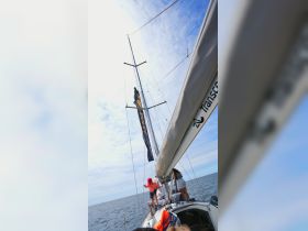 A lively sailing adventure featuring a group of people, including a child, enjoying the open ocean — perfect for family outings and nautical experiences.