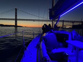 A serene evening view from a yacht with illuminated features, showcasing the stunning sunset and a bridge in the background — perfect for romantic cruises or sunset tours.